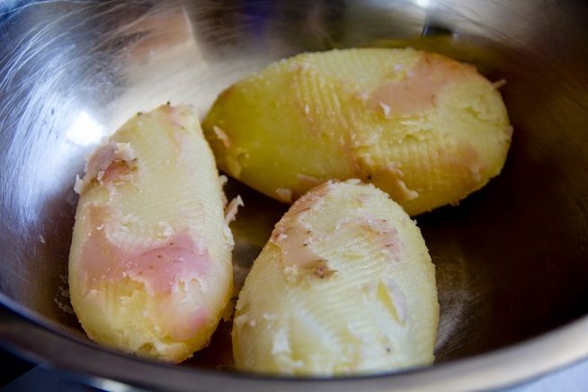את תפוחי האדמה המבושלים מחזיקים עם מגבת וקולפים בעזרת סכין (למתכון צריך רק 2). צילום: קרן ביטון כהן