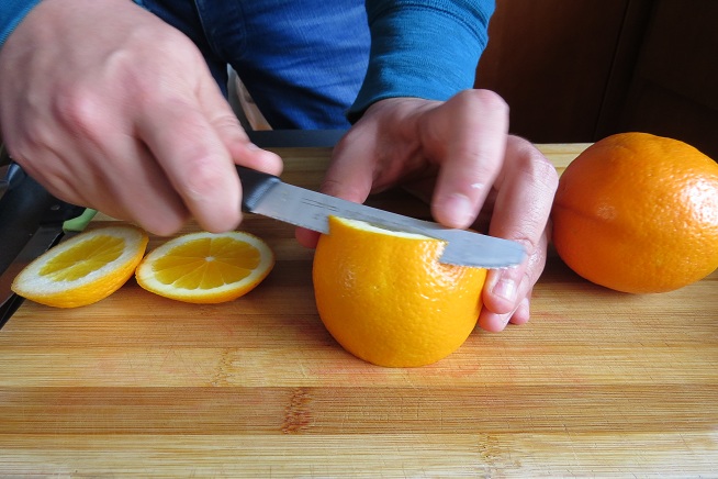 מורידים את הקצוות של התפוז וחותכים מסביב לחלק הכתום. צילום: שרון היינריך